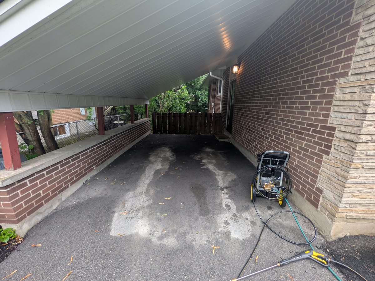 A covered driveway with pale salt staining across the asphalt